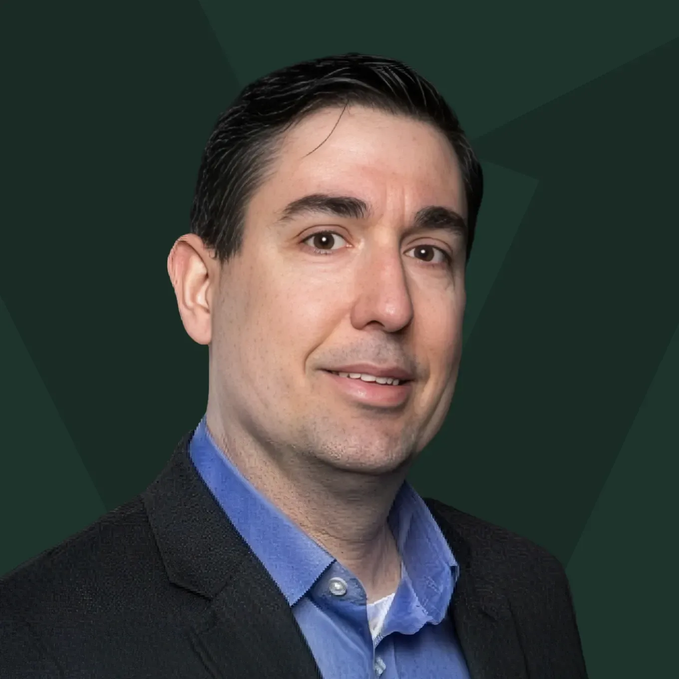 Portrait of a man in a dark blazer and blue shirt against a dark green background