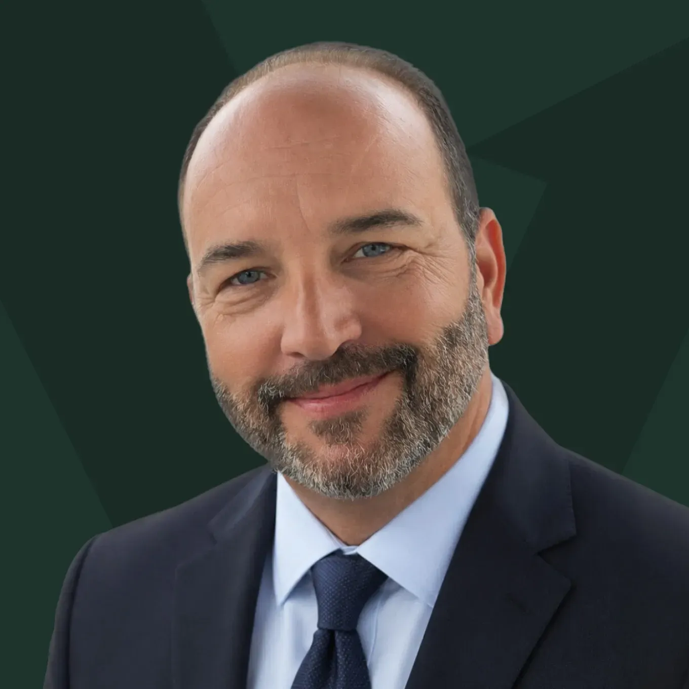 Portrait of a smiling man in a navy suit and tie against a dark green background