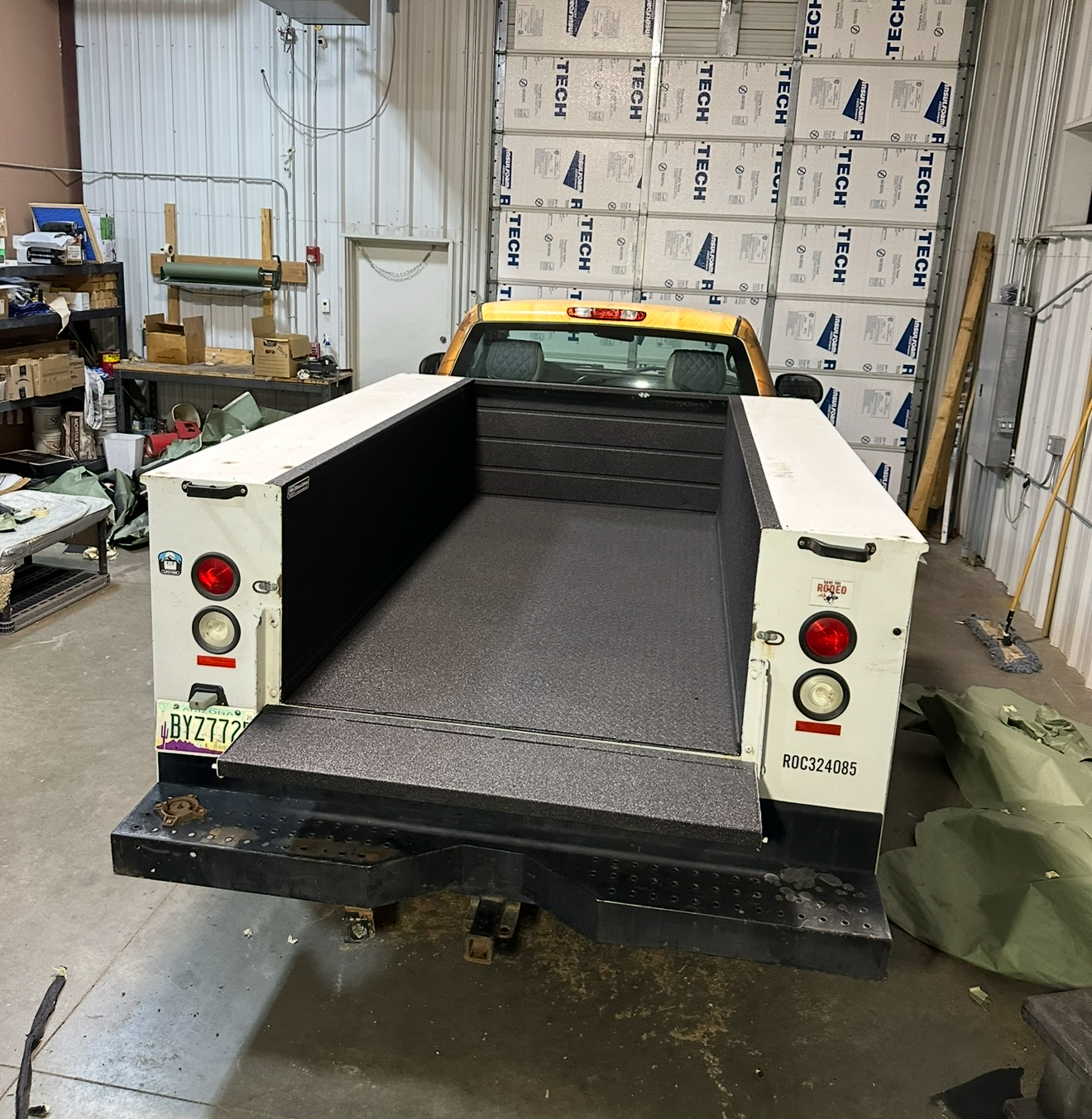 Yellow truck bed with white sides, black interior, and license plate.