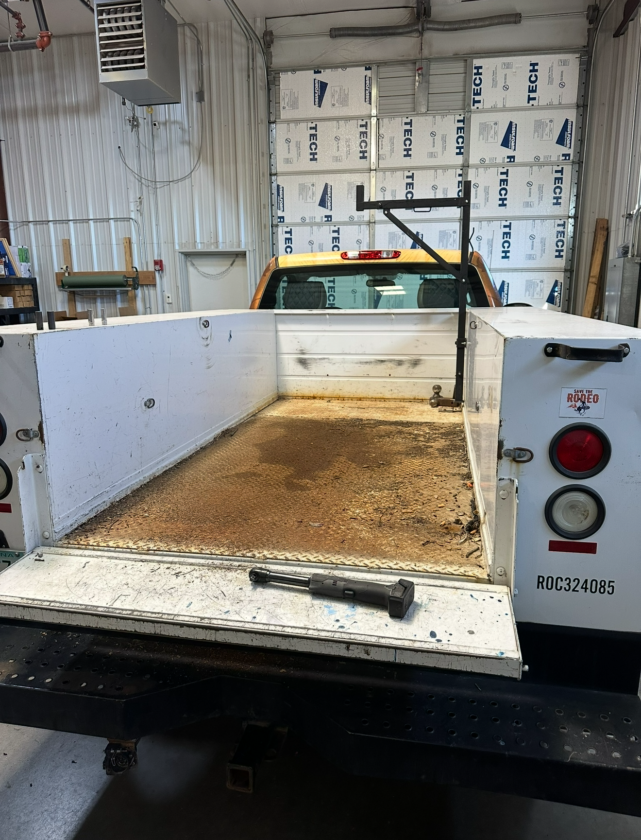White flatbed truck bed, brown interior, open in a garage setting.