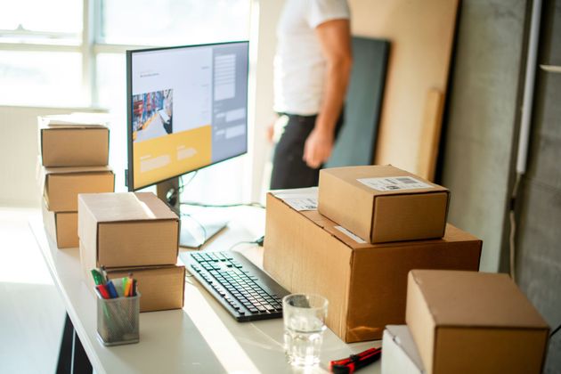 Packing boxes on an office desk beside a computer and keyboard, with a person in the background Packing boxes on an office desk beside a computer and keyboard, with a person in the background