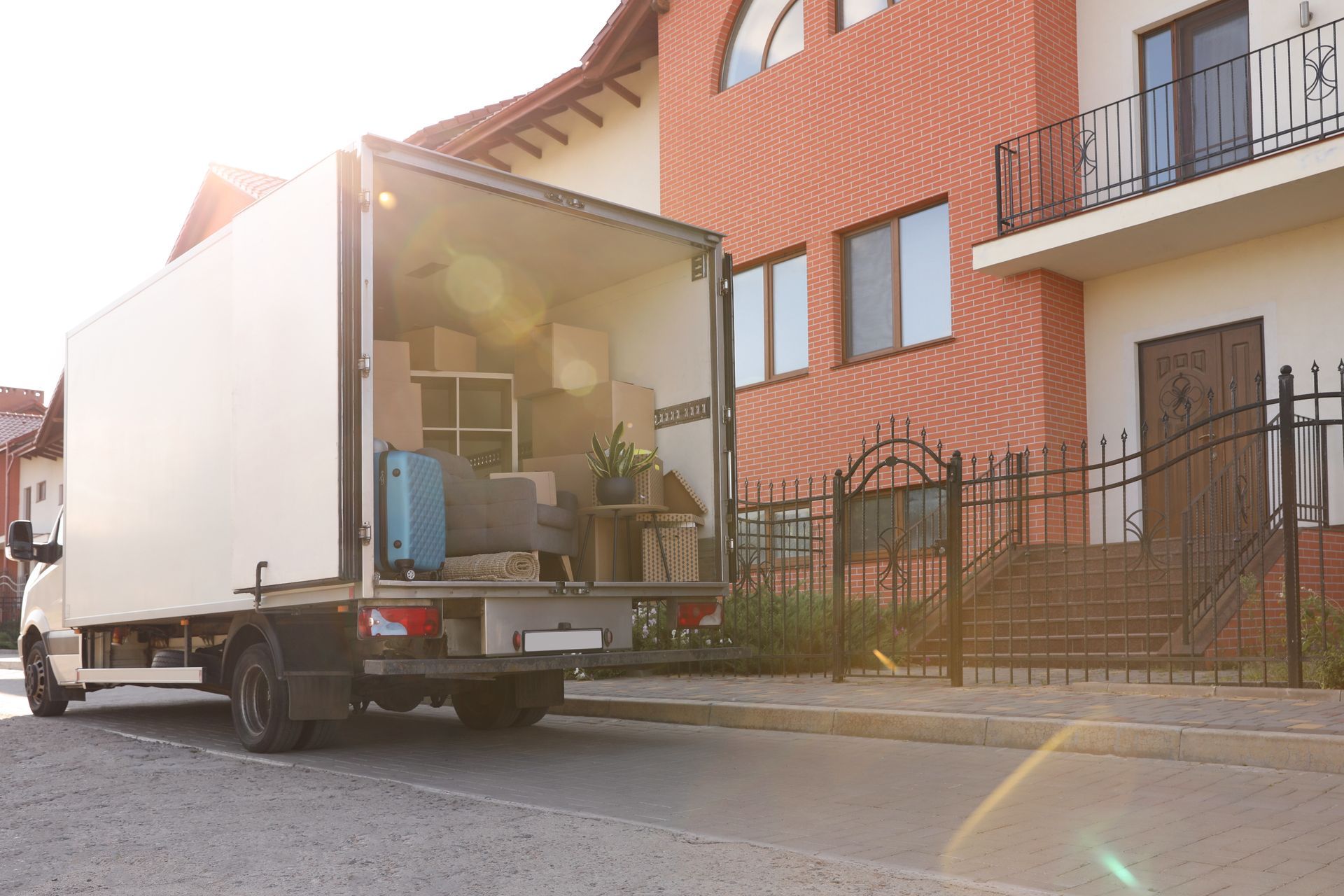 Moving truck with open rear parked on a street beside brick apartment buildings. Moving truck with open rear parked on a street beside brick apartment buildings.