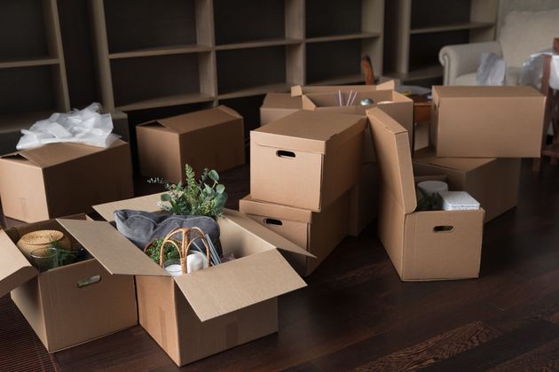 Open cardboard boxes and packing supplies scattered across a room floor. Open cardboard boxes and packing supplies scattered across a room floor.