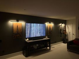 Modern hotel room with a wall-mounted control panel and a desk by a window and lamp
