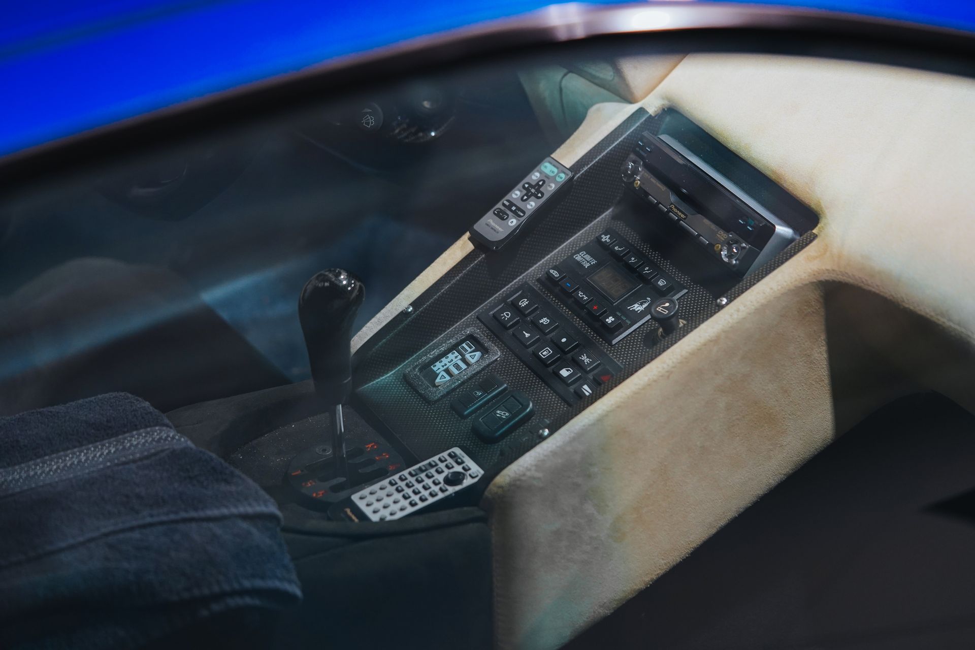 Interior car console with gearshift, radio, and remote. Beige and black elements.