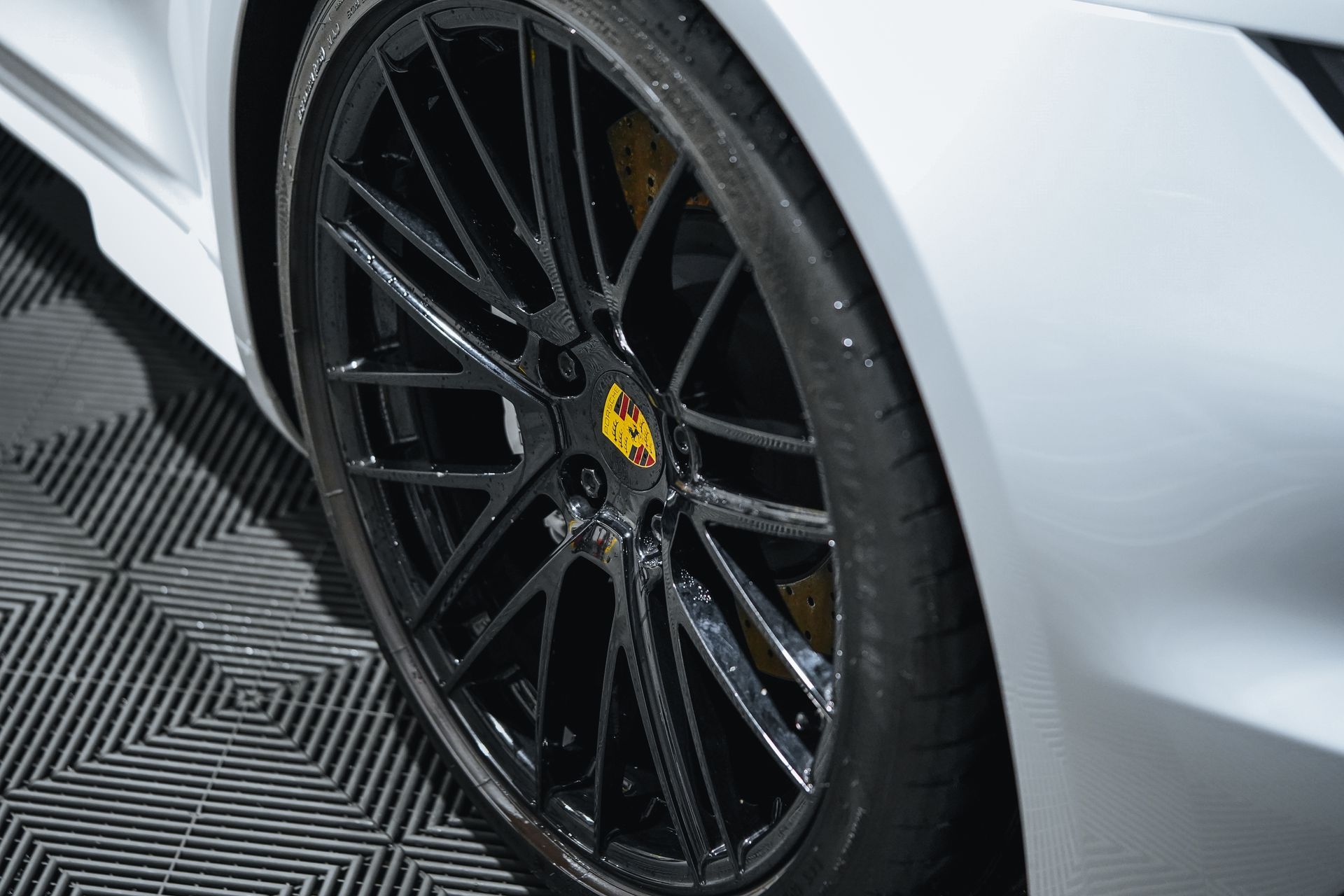White Porsche with a black rim and yellow brake calipers.