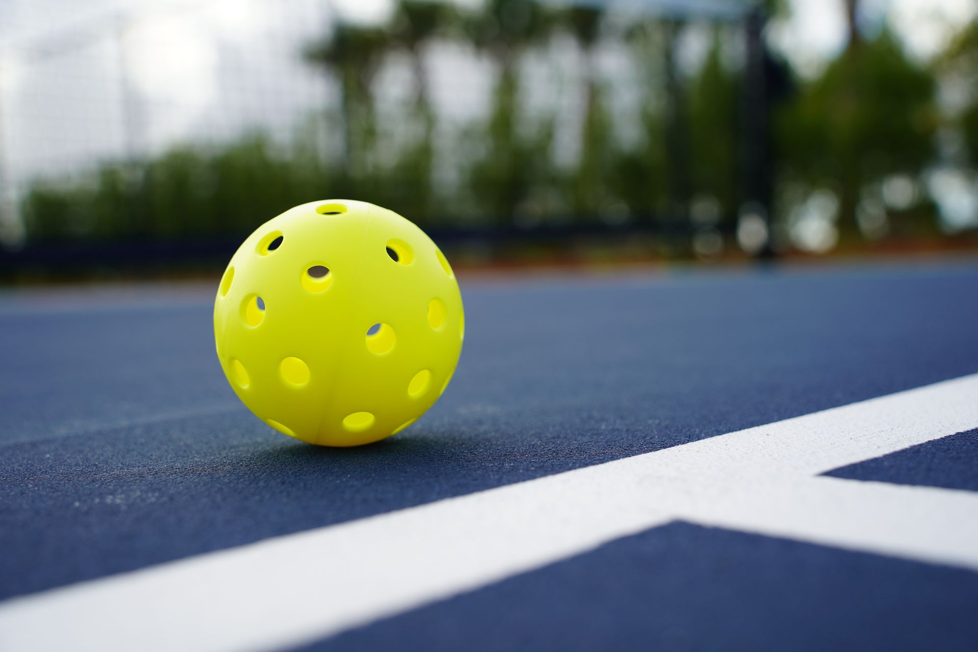 A yellow ball is sitting on top of a blue tennis court.