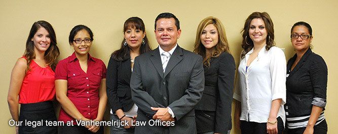 Six-person legal team posing in an office, with one man in a gray suit centered in front.