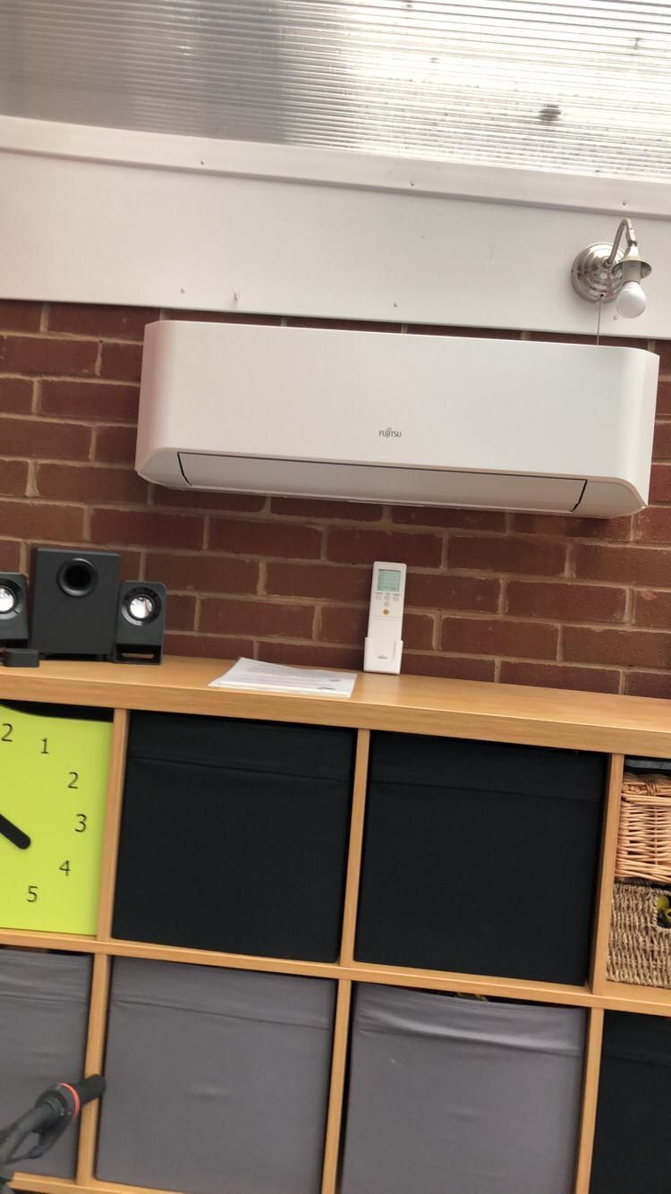 Classroom wall with brick backdrop, white cabinet, speaker, clock, and cubby shelves with bins