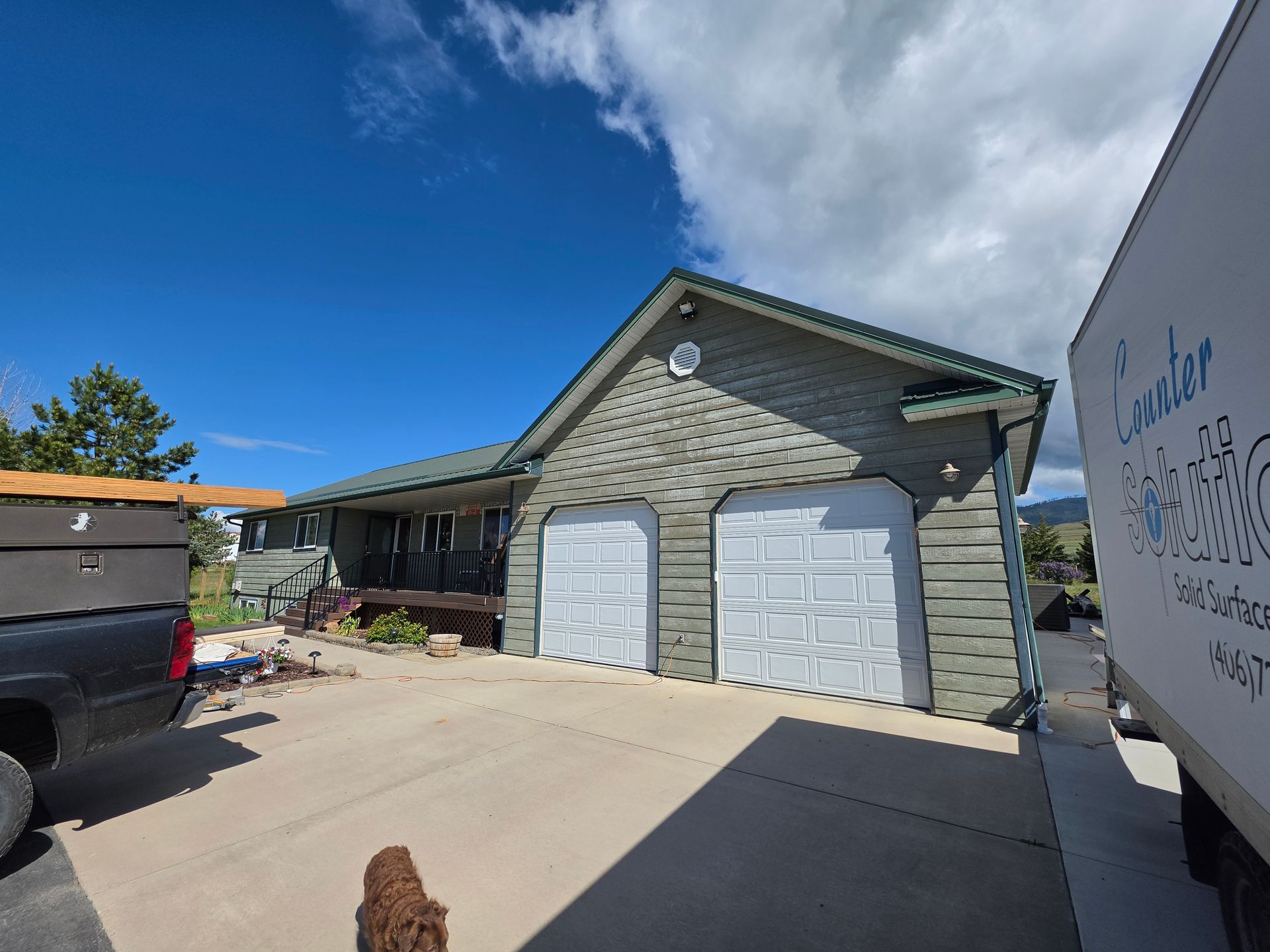 Suburban house with three white garage doors under a blue sky, viewed from the driveway.