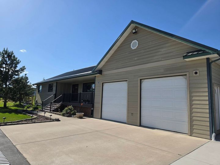 Suburban house with two white garage doors and a concrete driveway under a blue sky