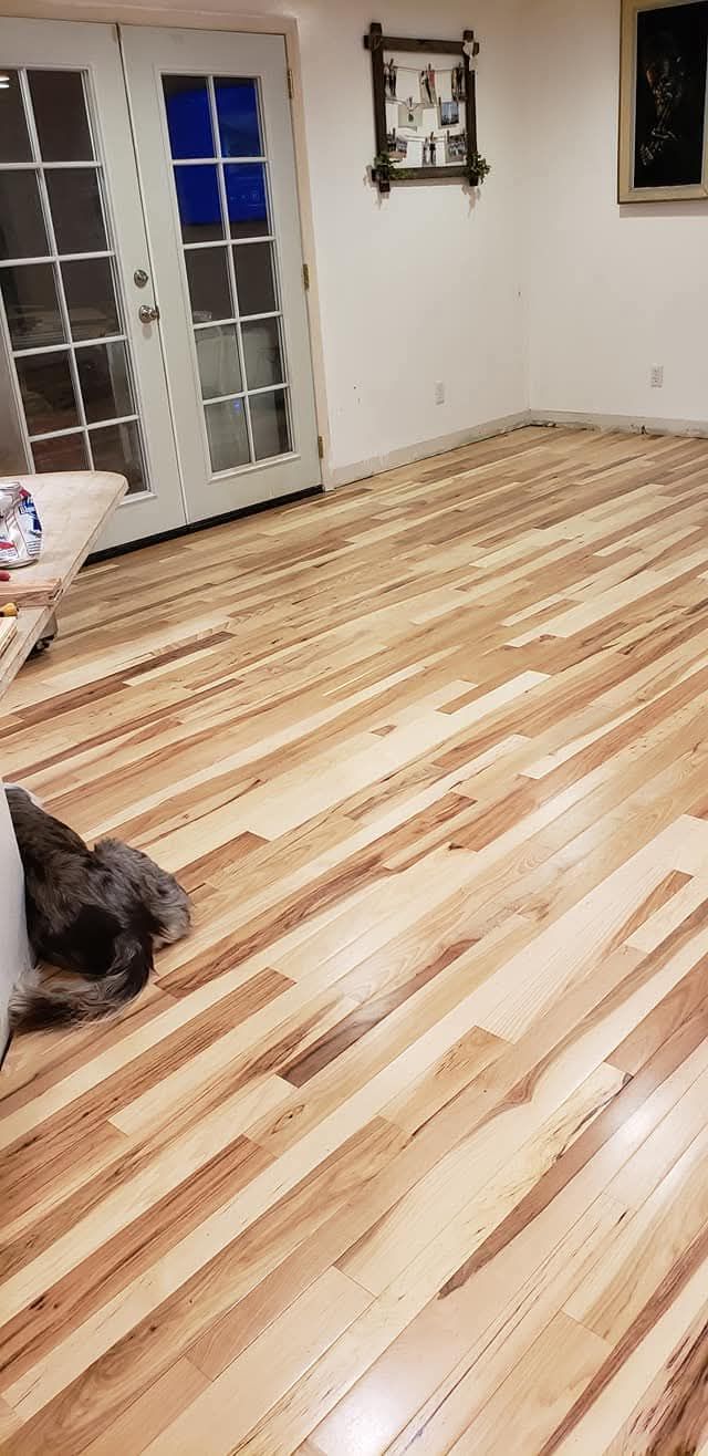 Empty room with newly finished light wood flooring, white walls, and a glass door
