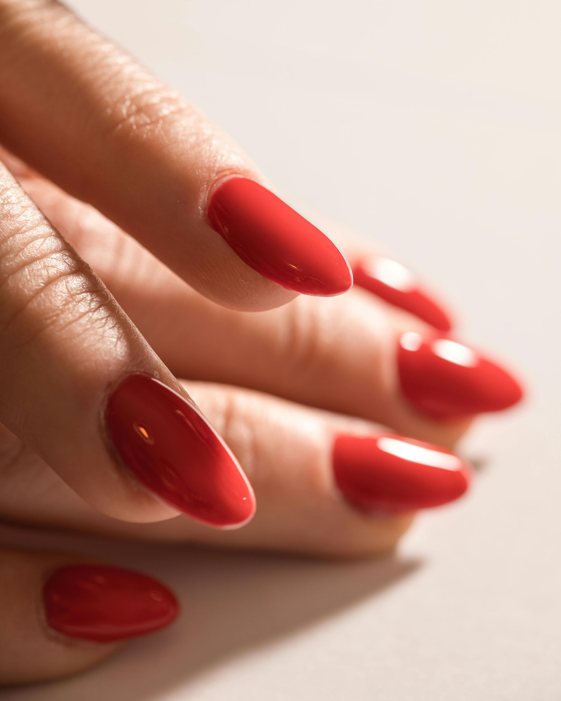 Hand with oval, glossy red fingernails.