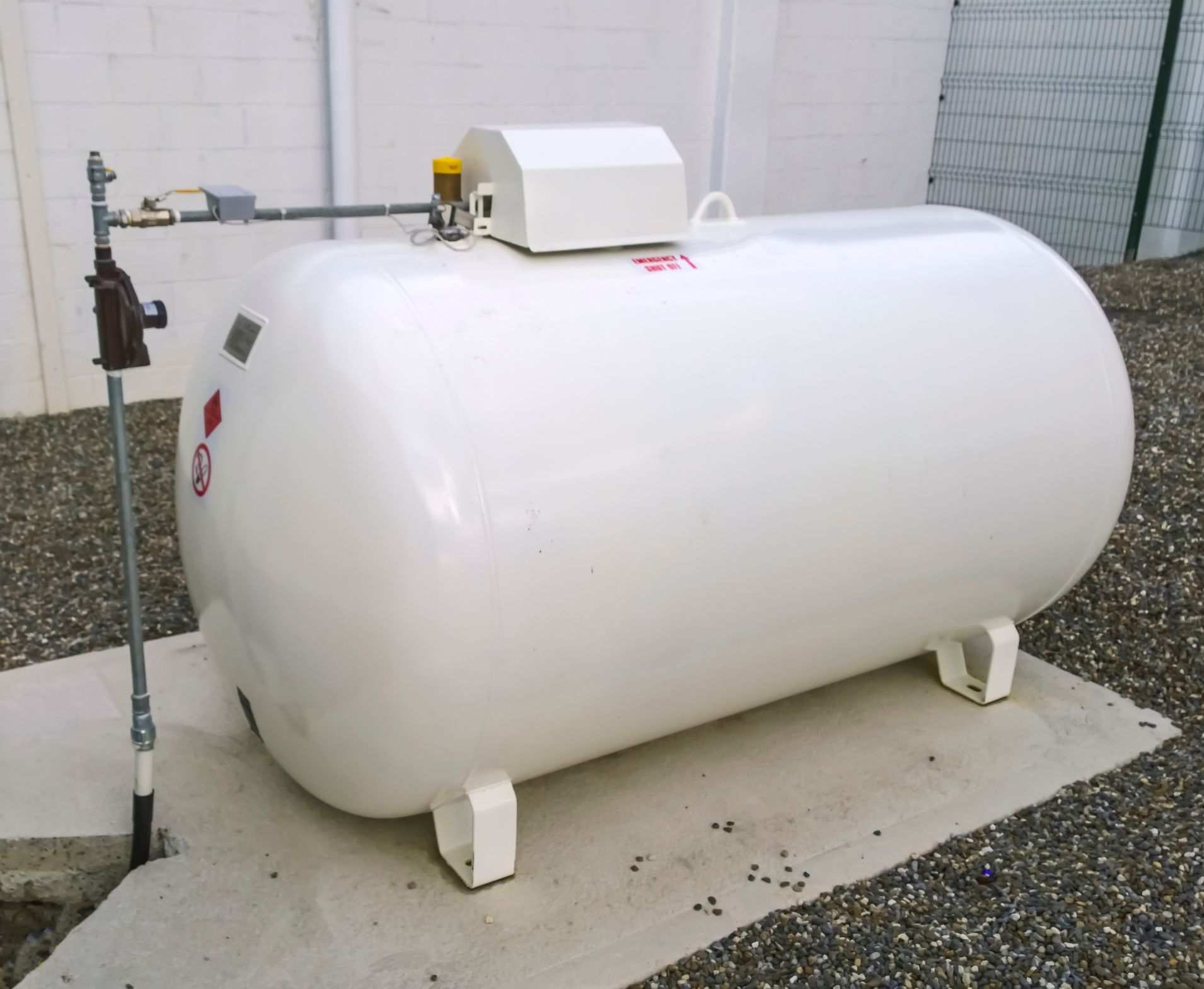A large green propane tank is sitting in the middle of a lush green yard.