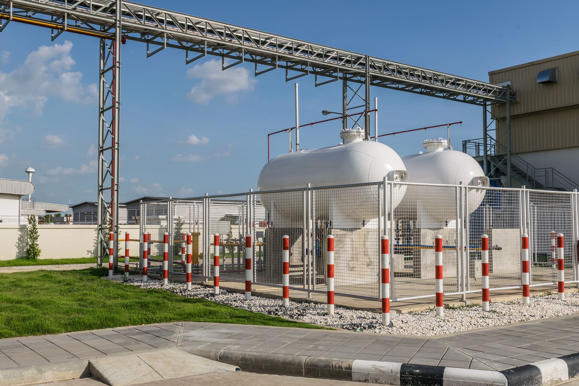 There are two large tanks in a fenced in area in front of a building.