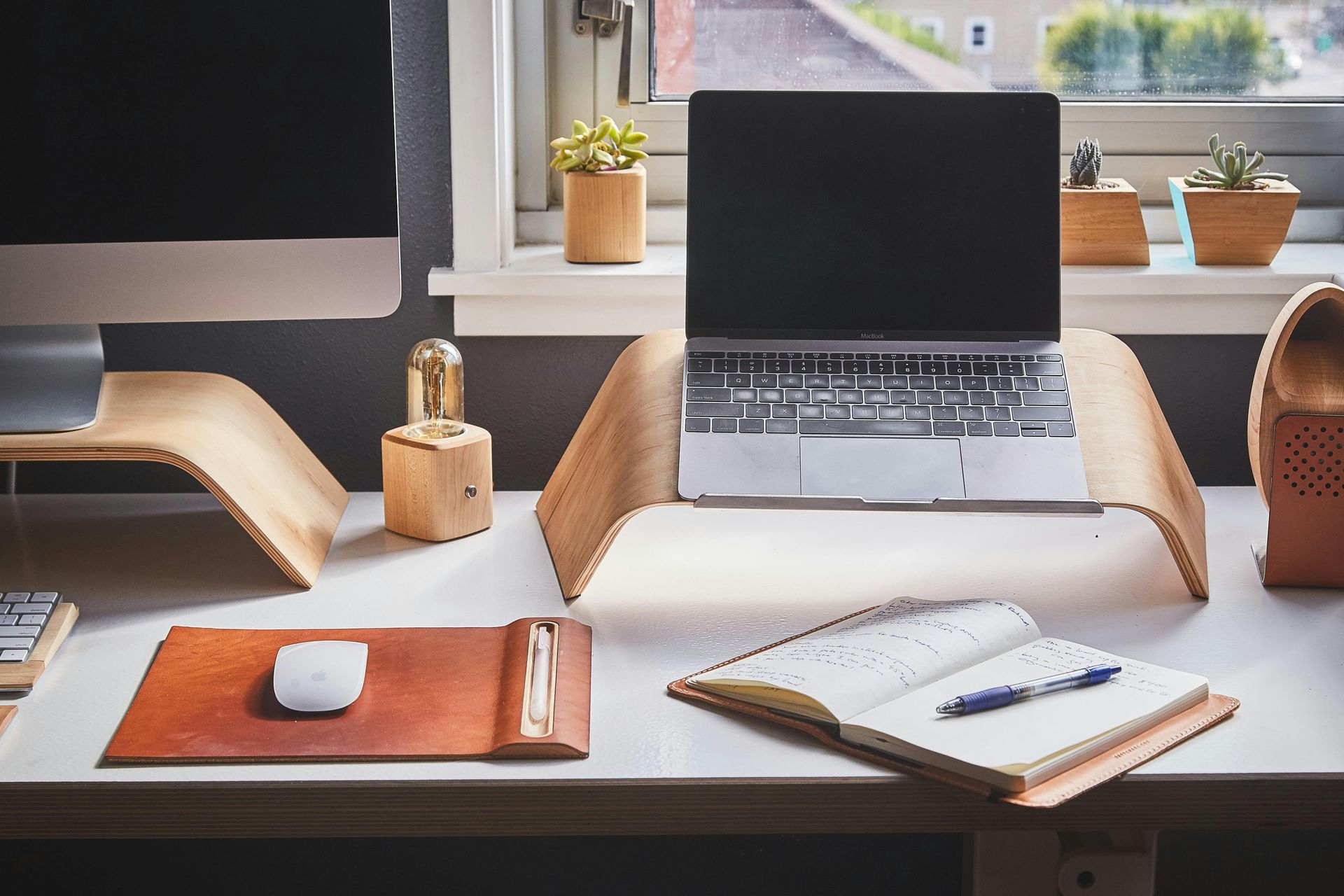 A laptop is sitting on a wooden stand on a desk.