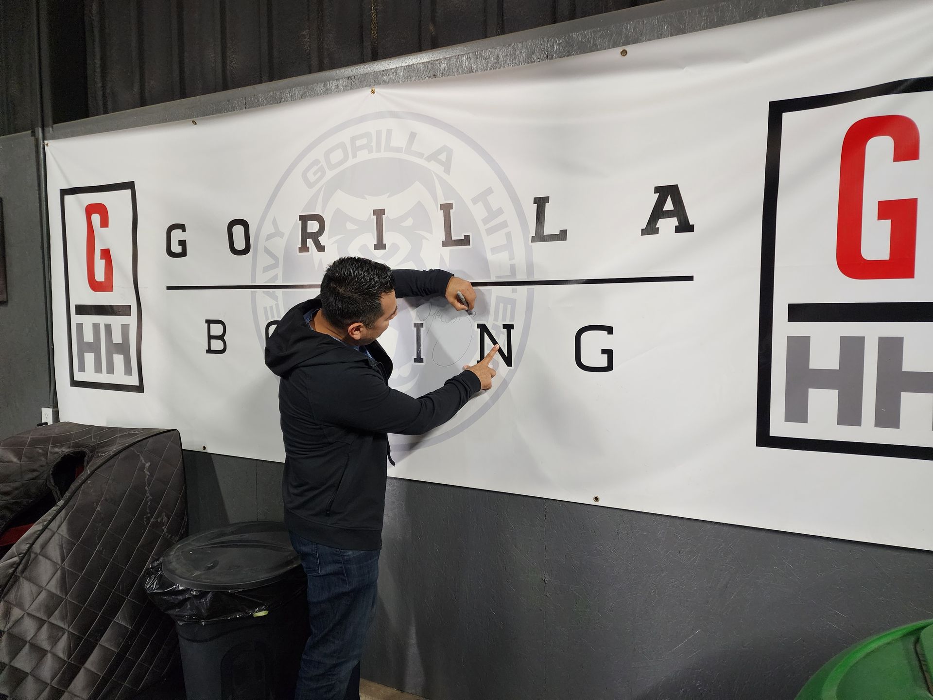 Person spray-painting a Gorilla Boxing wall mural in a gym-style interior