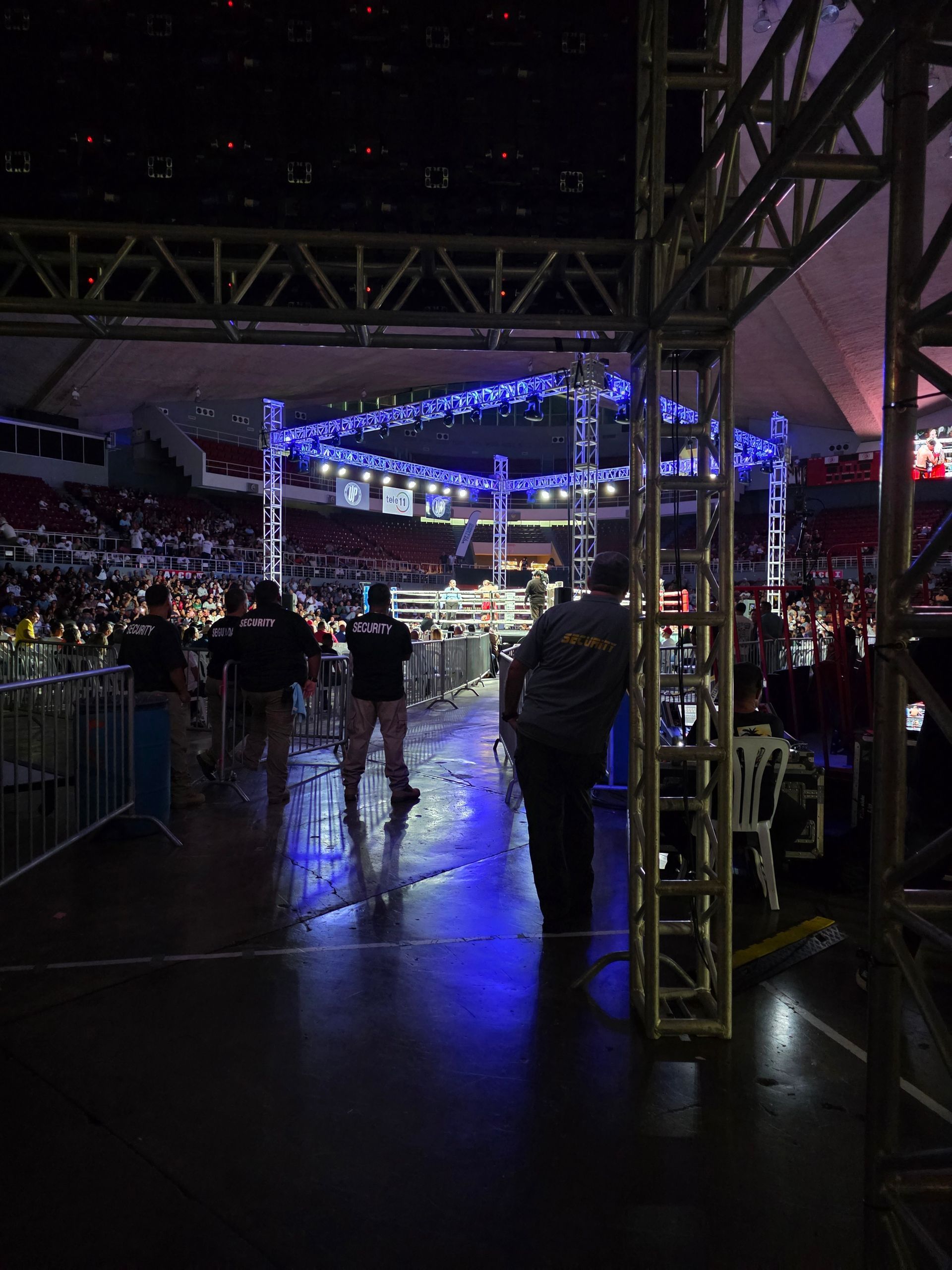 Concert arena walkway with stage lights and crowd seating in the background