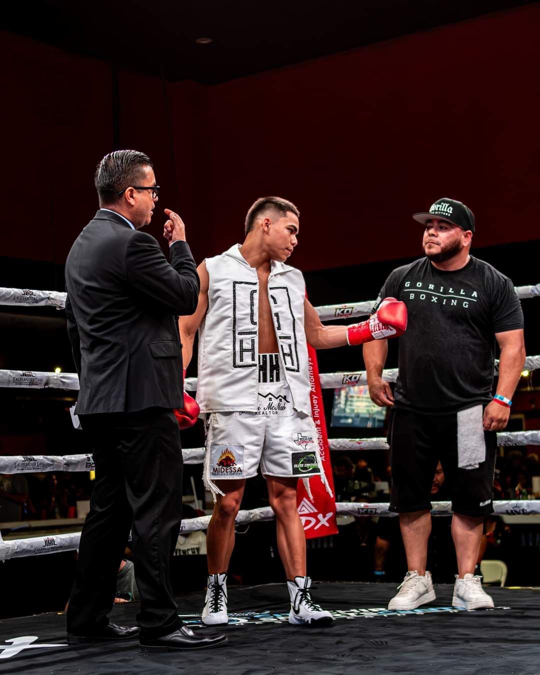 Boxing ring scene with referee, fighter in white gear, and coach in black