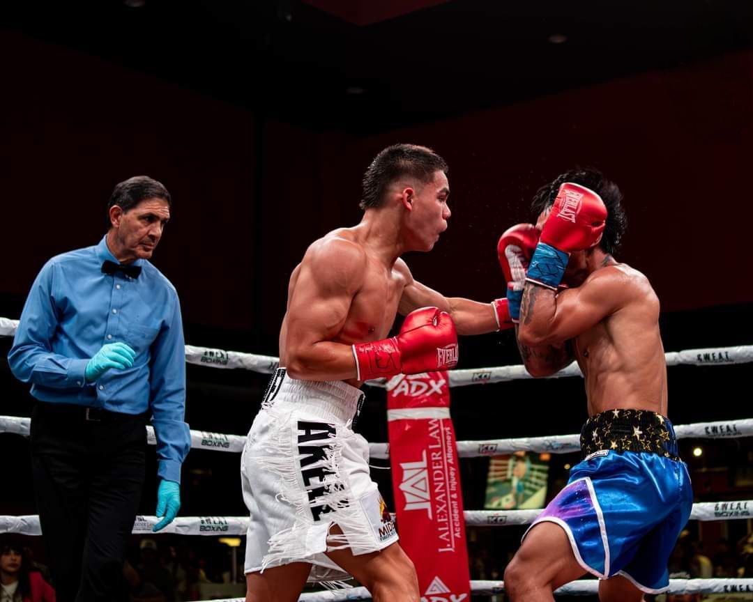 Two boxers trade punches in a ring while a referee watches closely