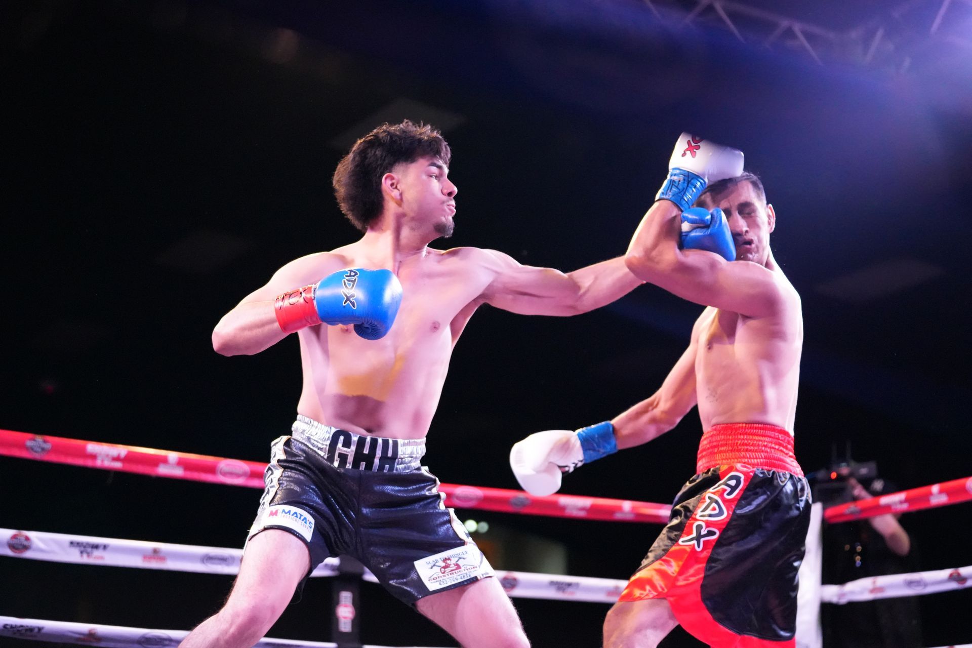 Two boxers sparring in a ring, one throwing a punch while the other blocks with blue gloves.