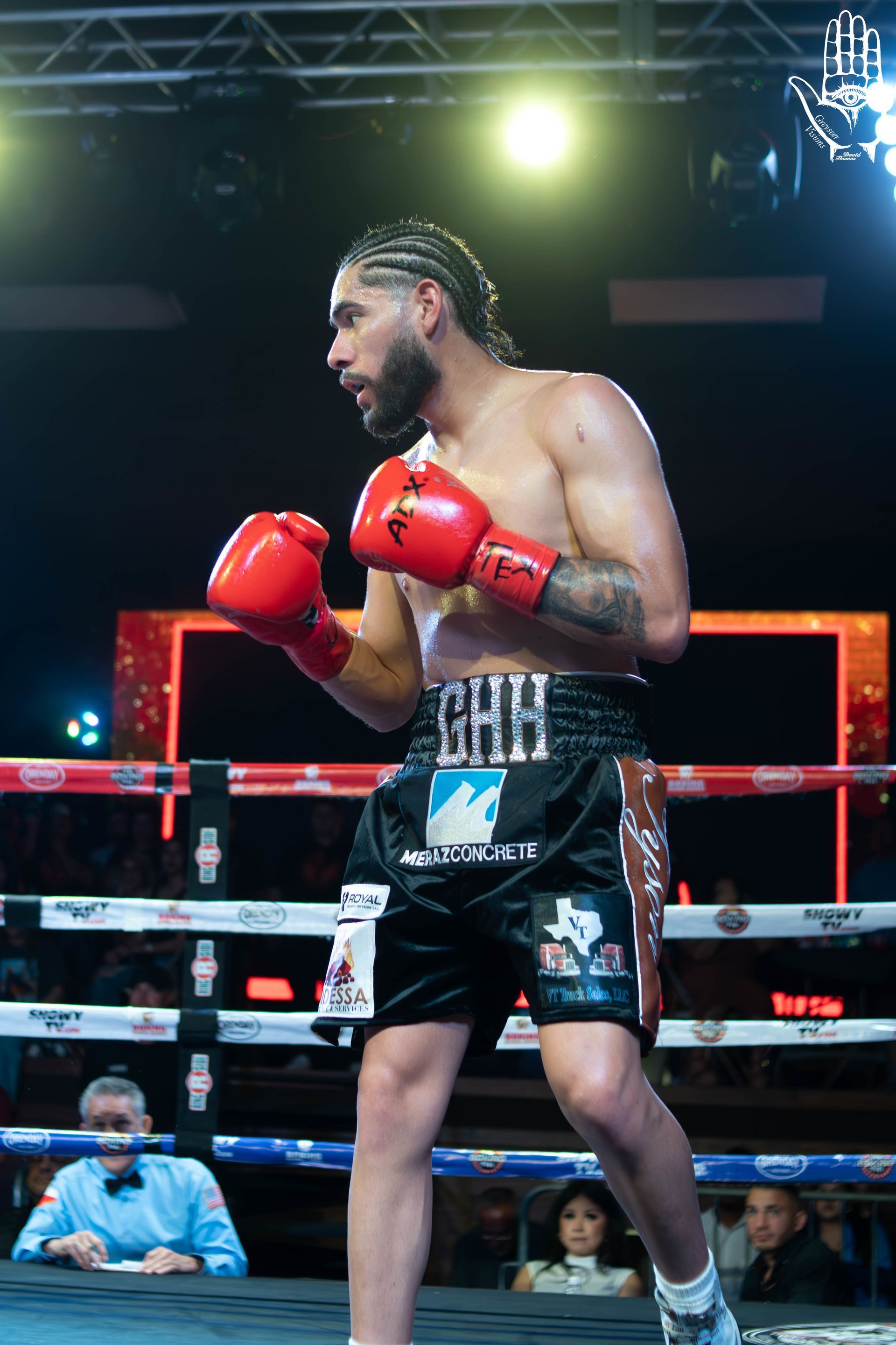 Boxer in red gloves standing in a ring under bright arena lights, ready to fight
