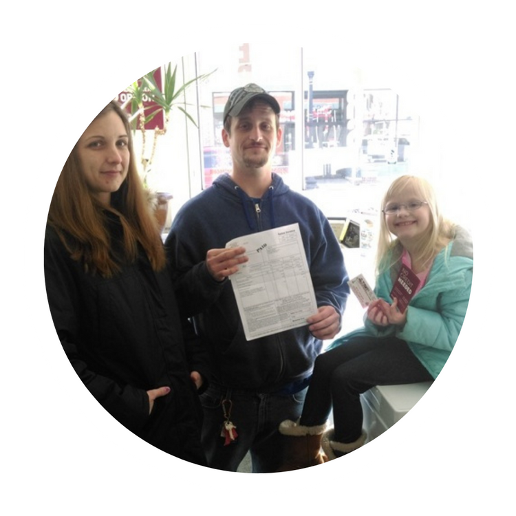 Three people indoors, one holding a document and another holding a card, posing for a photo.