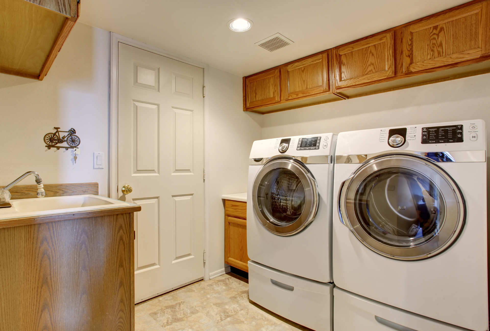 Laundry room with a washing machine and dryer, cabinets, and a sink.
