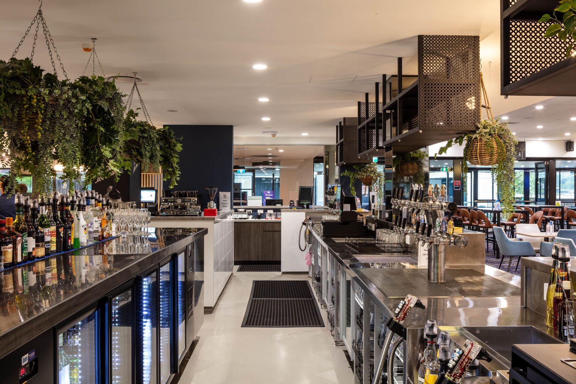 Modern restaurant bar interior with counters, hanging plants, and warm lighting