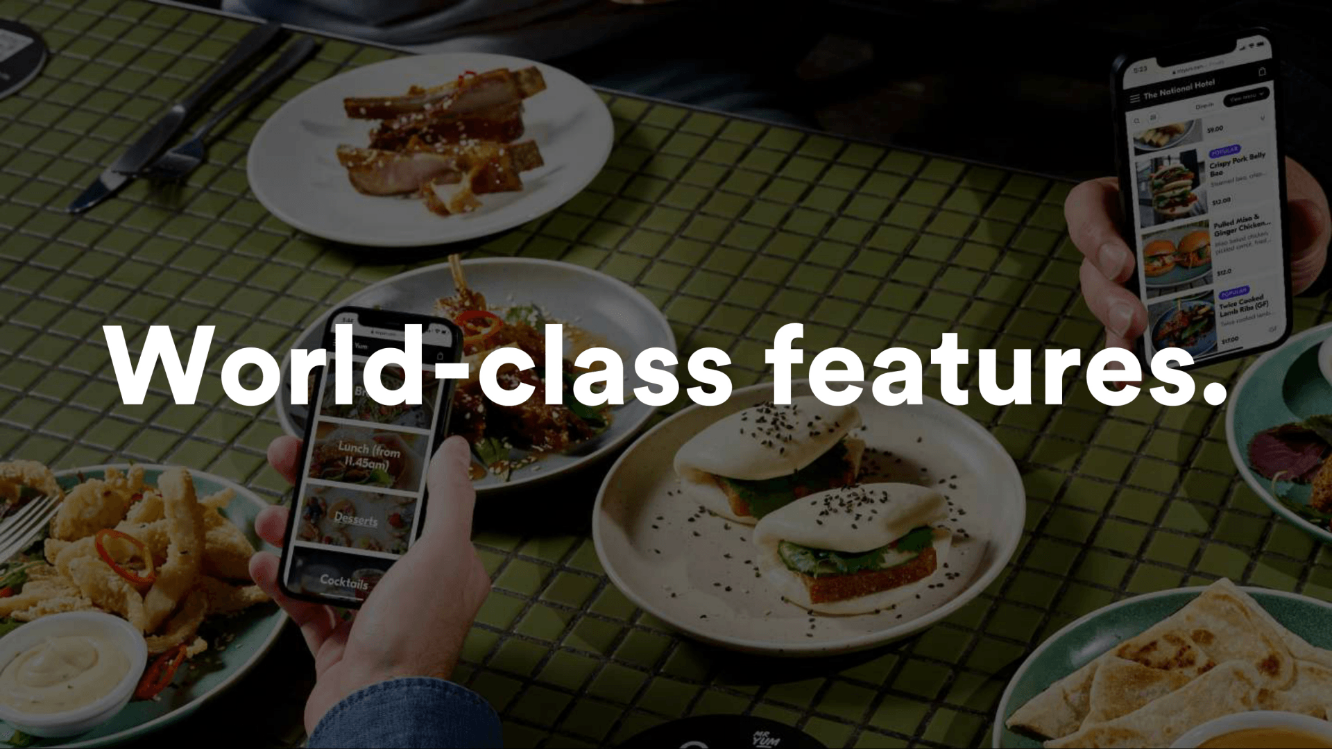A person is holding a cell phone in front of a table with plates of food.