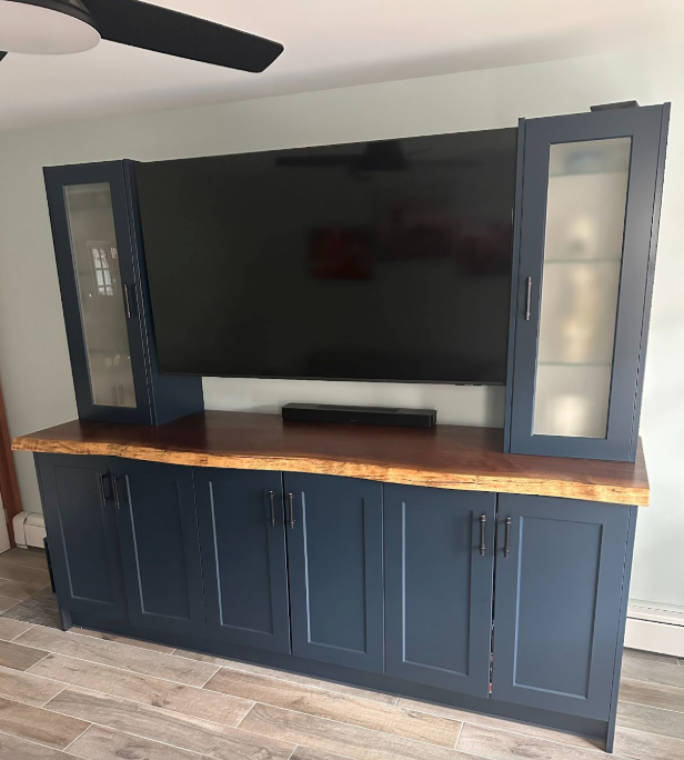 Large flat-screen TV on a dark blue cabinet with wood top, flanked by glass-front cabinets in a living room.