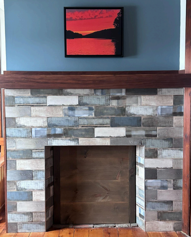 Stone fireplace with dark wood mantel and a red landscape painting above it.