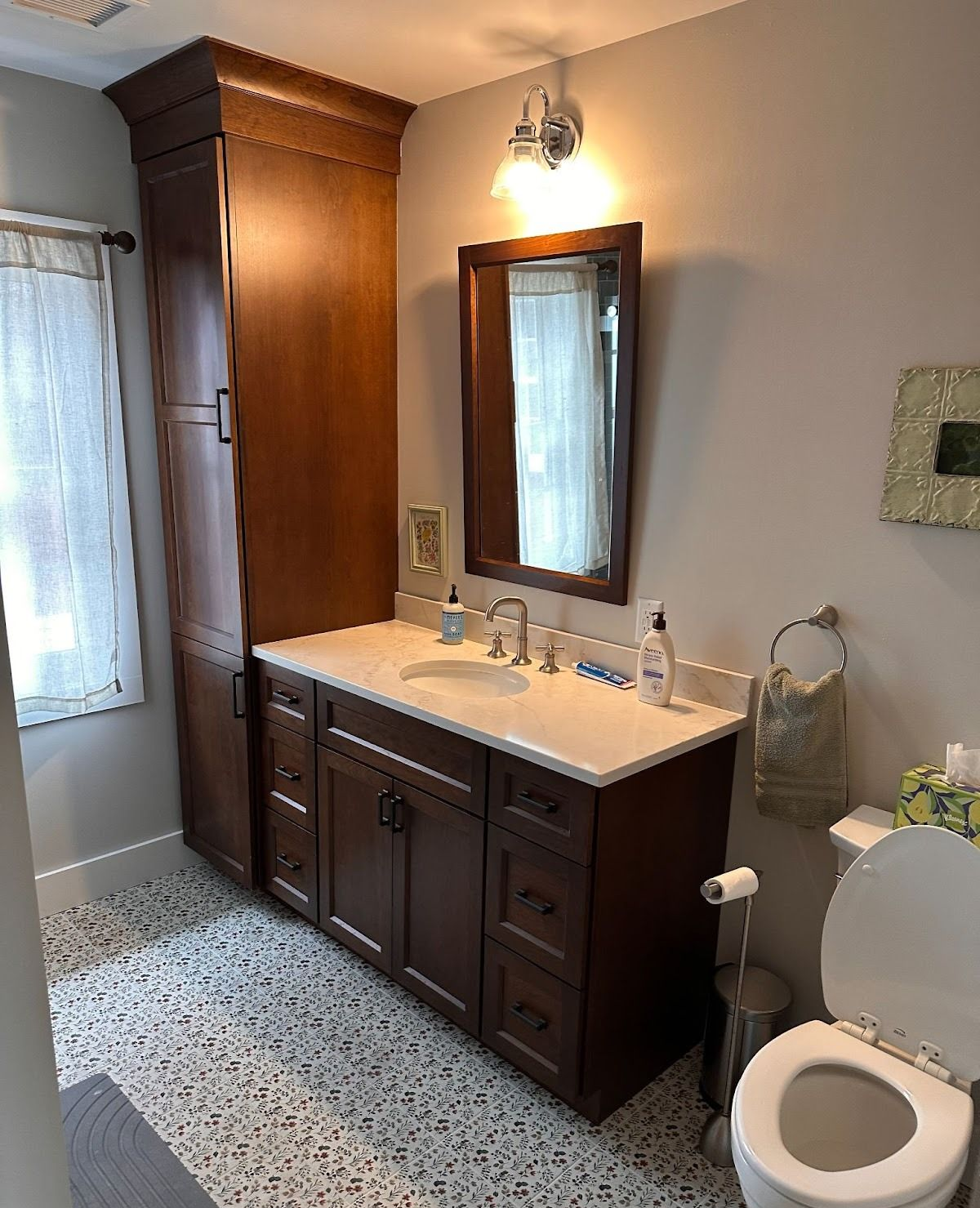 Elegant bathroom with dark wood vanity, white countertop, mirror, wall sconce, and toilet