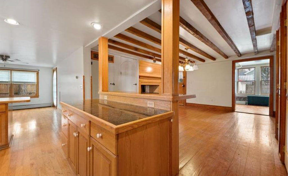 Open-plan living area with wood beams, hardwood floors, and a central kitchen island.