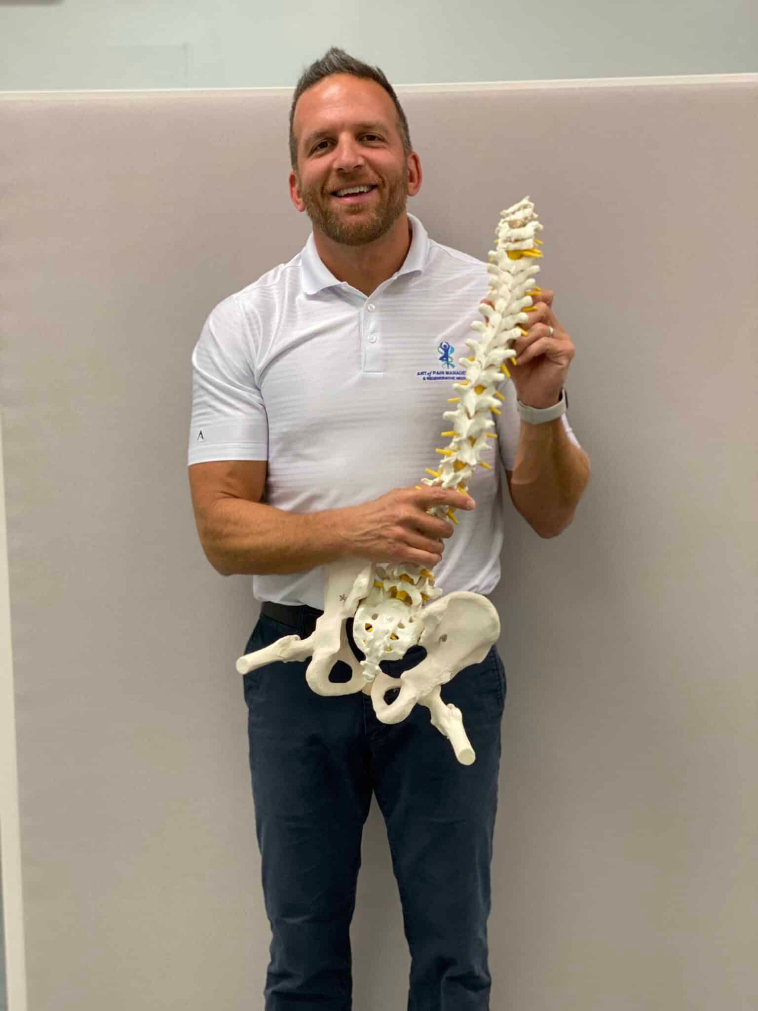 Dr Teller holding a model of a spine and a pelvis