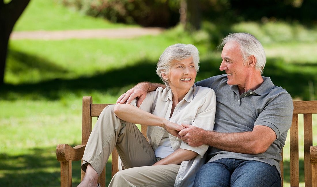 a man and woman are sitting on a park bench