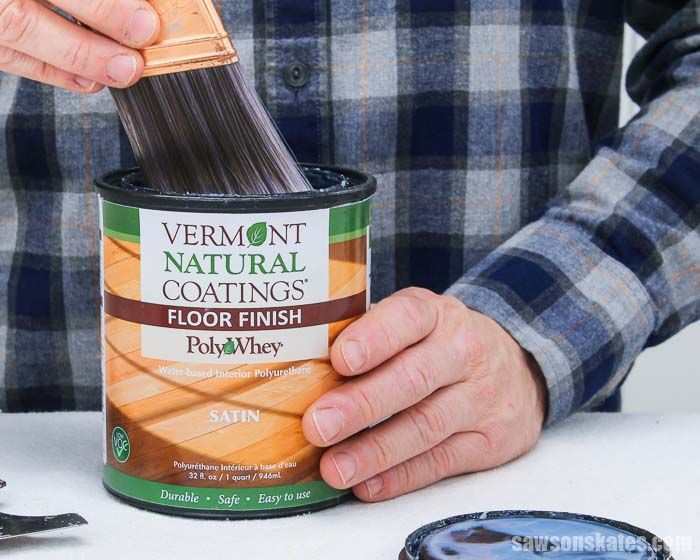 Hands brushing finish onto a Vermont Natural Coatings wood finish can on a table.
