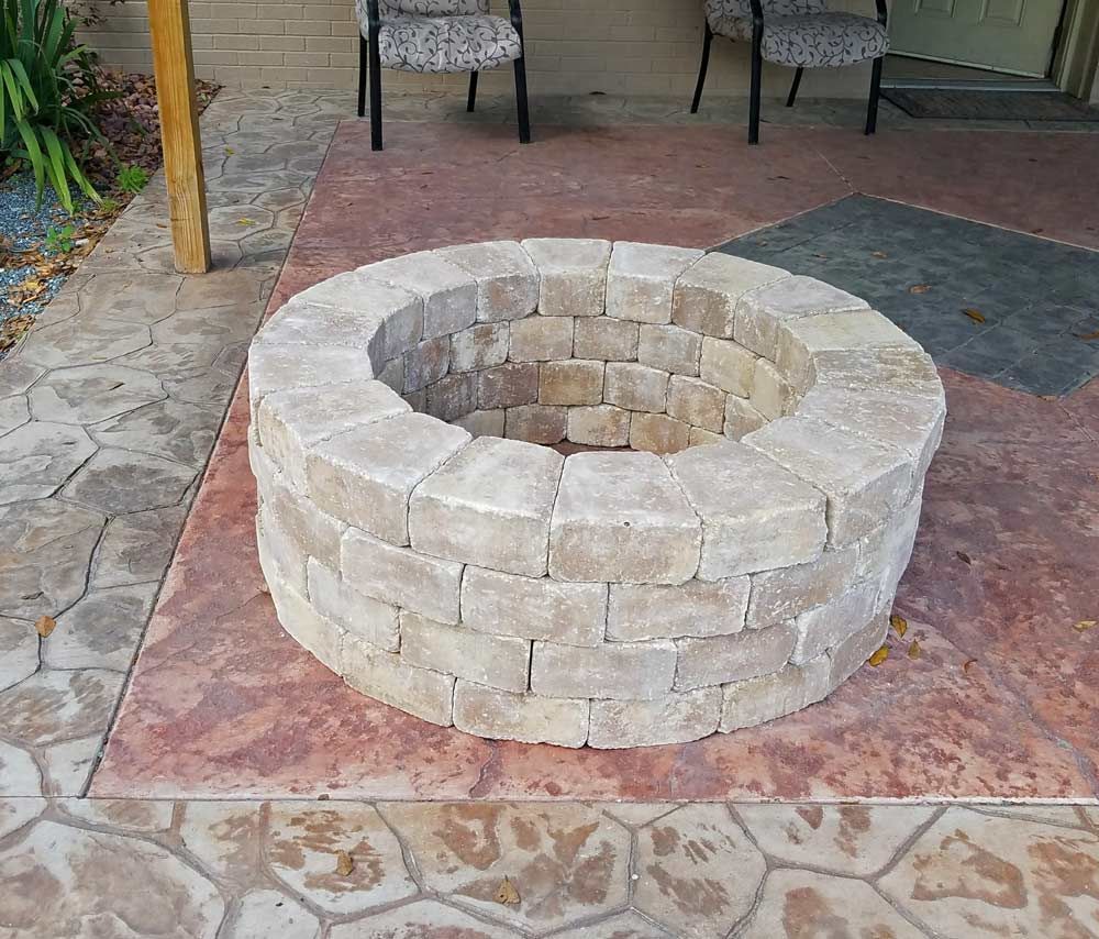 Stone fire pit centered on a patio, with tan bricks and a circular opening