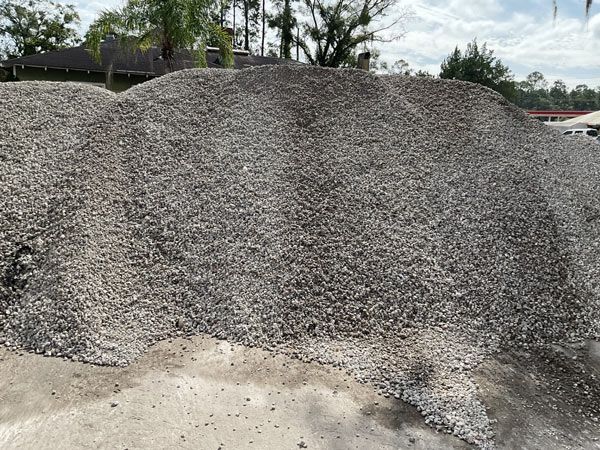 Large gray gravel pile in an outdoor yard under a cloudy sky