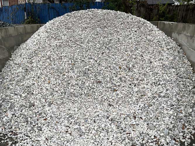 Large pile of white gravel or crushed stone in an outdoor storage area