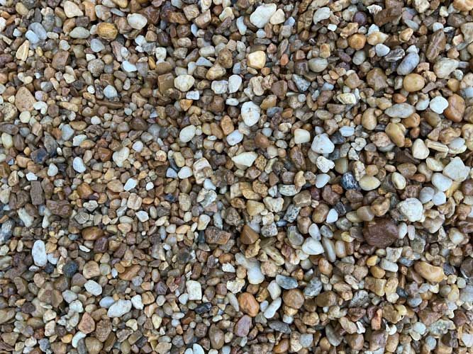 Close-up of small beige, brown, and white pebbles covering the ground