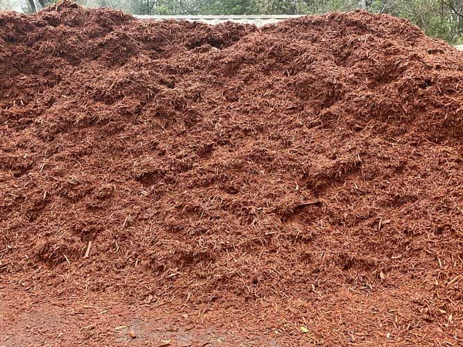 Large pile of reddish-brown mulch or wood chips outdoors