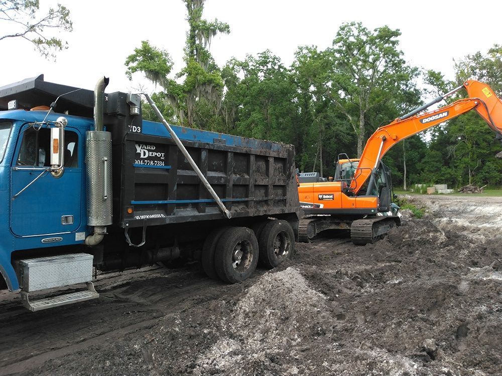 Blue dump truck and orange excavator working in a muddy construction site