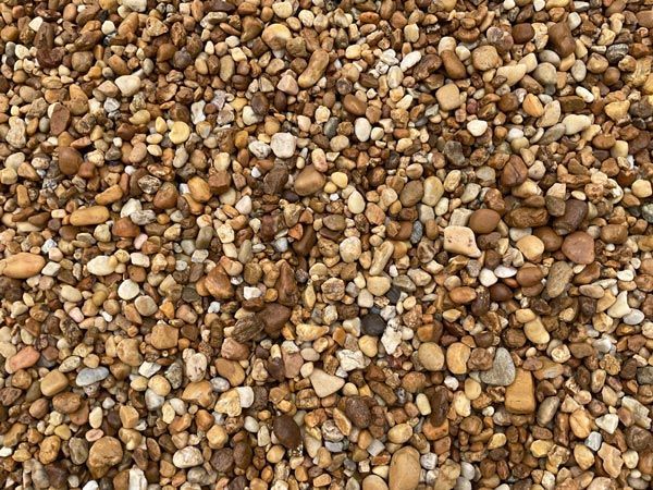 Close-up of mixed tan, brown, and white pebbles covering the ground