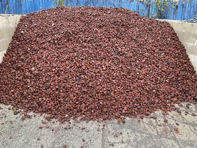 Large pile of reddish-brown gravel or stones in a concrete bin outdoors