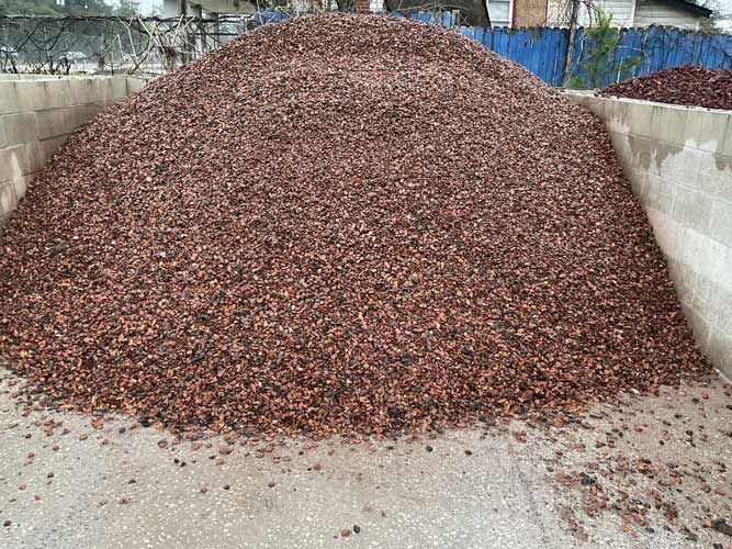 Large pile of reddish-brown gravel or crushed stones in a concrete-walled storage area
