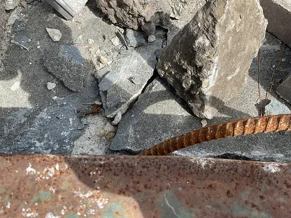 Broken concrete and rubble with a rusted metal rod in the foreground