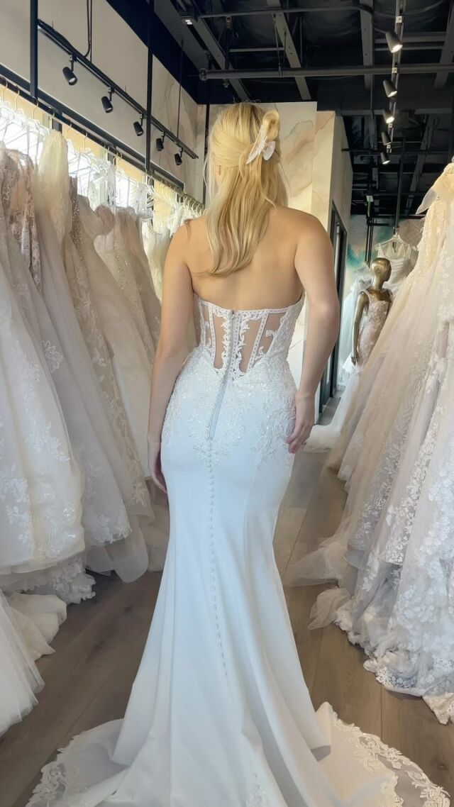 A woman is trying on a wedding dress in a bridal shop.