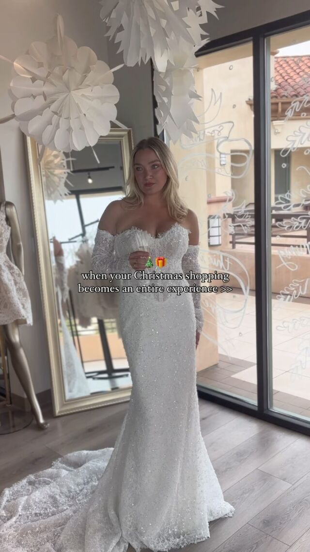 A woman in a wedding dress is standing in front of a mirror.
