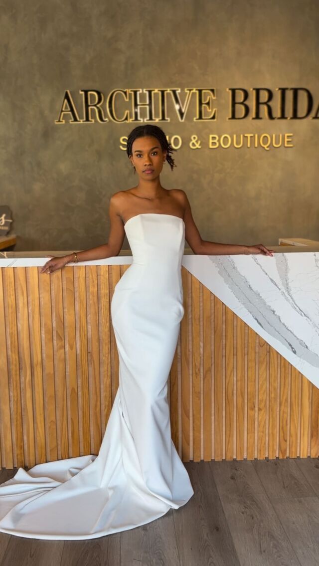 A woman in a white dress is standing in front of a counter.
